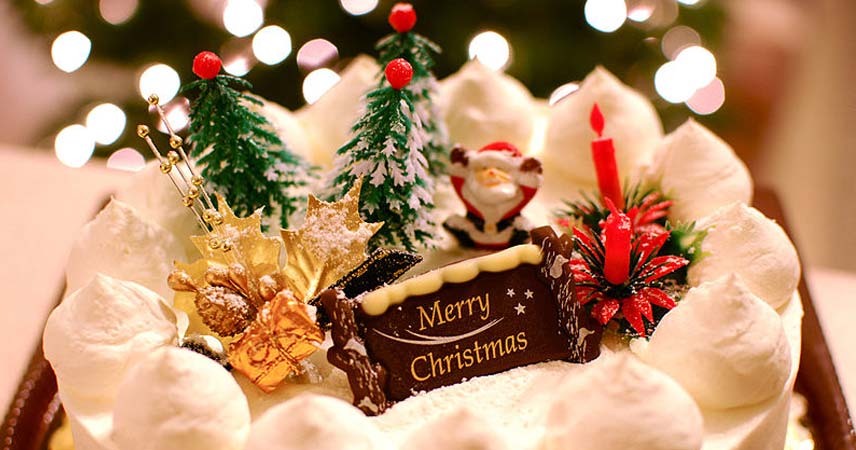Close up shot of a Christmas cake decorated with white icing and a Christmas tree and Santa Claus figure