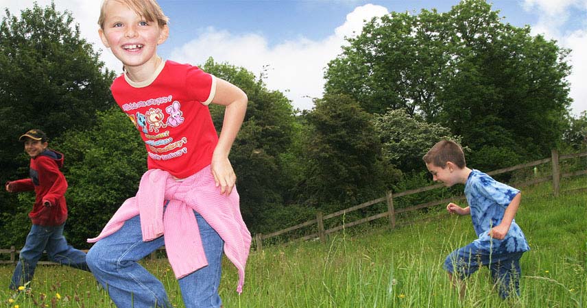 Three children running in a field on a sunny day at Bosinver