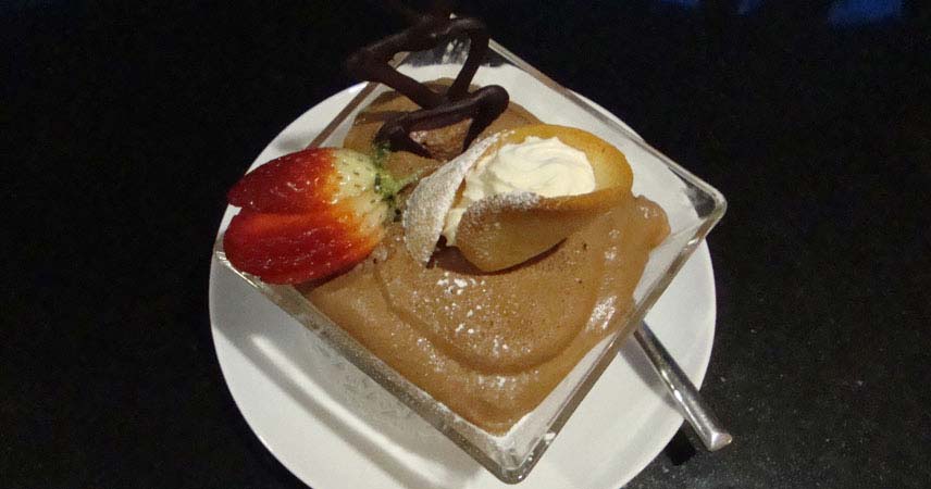 Close up of a chocolate dessert topped with a strawberry, cream and chocolate decoration
