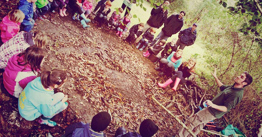 Group of guests listening to a man speak outdoor at Bosinver. The guests are a mix of adults and children.