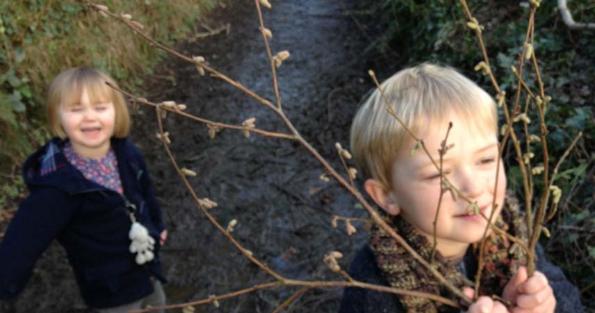 Two children walking down a country path as winter starts to turn to spring in Cornwall.
