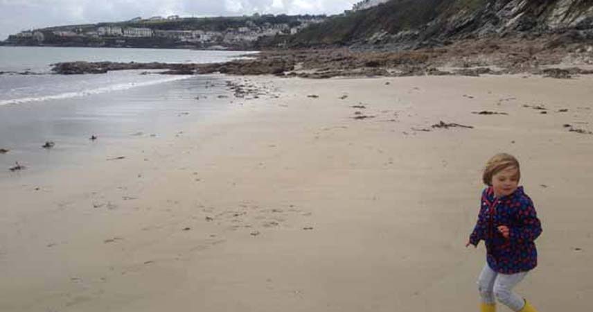 Small child running on a beach at Portscatho beach in Cornwall.