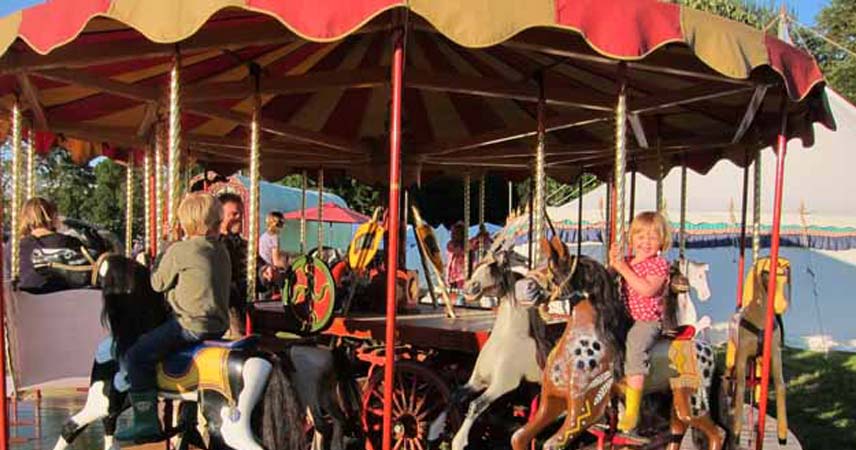 Two children on the Merry-Go-Round at Port Eliot in Cornwall, smiling for the camera.