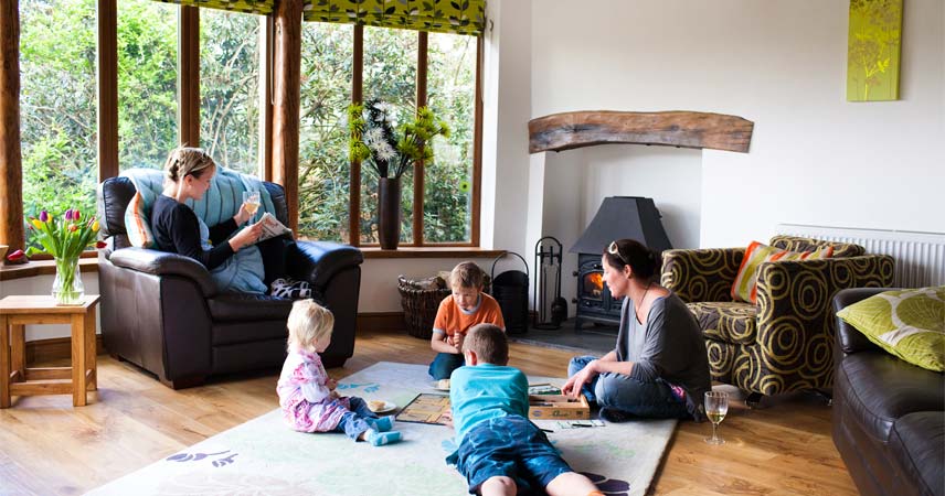 Family playing together in a lounge at Bosinver, with the fire on.