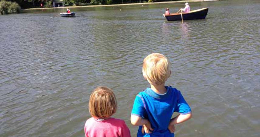 Two children watching the boats row by at Helston Boating Lake in Cornwall.