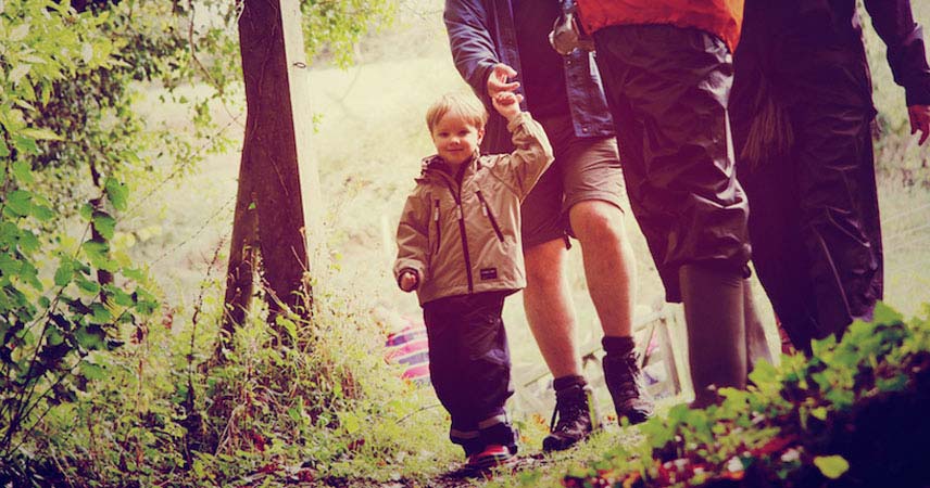 Three adults and a child walking in Cornwall through the countryside, all with coats on.