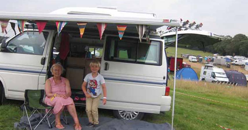 Two people outside of a campervan at Port Eliot festival on a grey day.