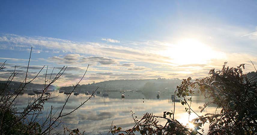View of River Fal at sunset, with boats moored on the river.