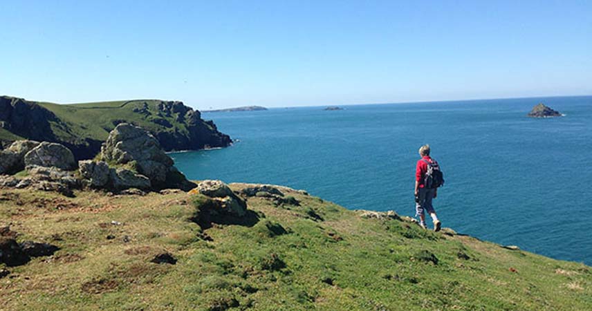 Walker on the coastline at Polzeath in Cornwall on a very sunny day.