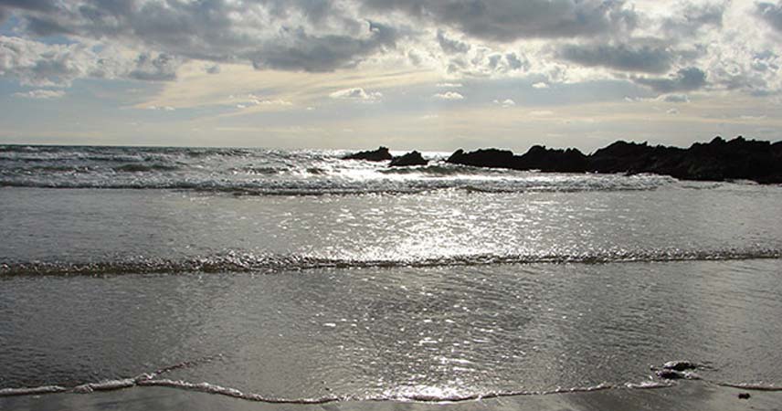 Waves rolling into the beach in Cornwall, glistening from the sun.
