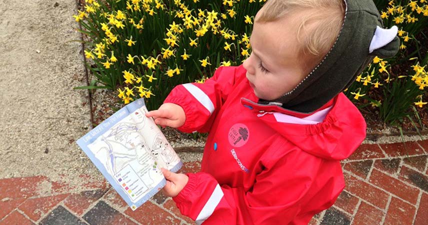 Toddler in a red coat exploring gardens of Heligan.