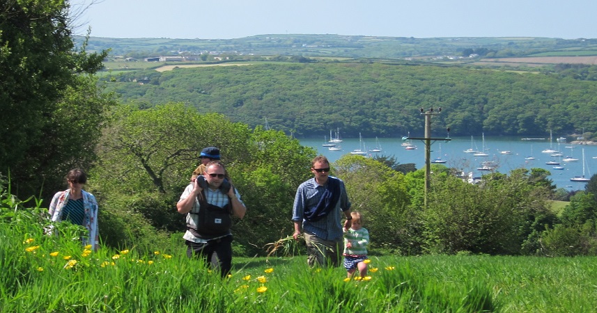 Three adults walking up a hill on the riverside with two small children