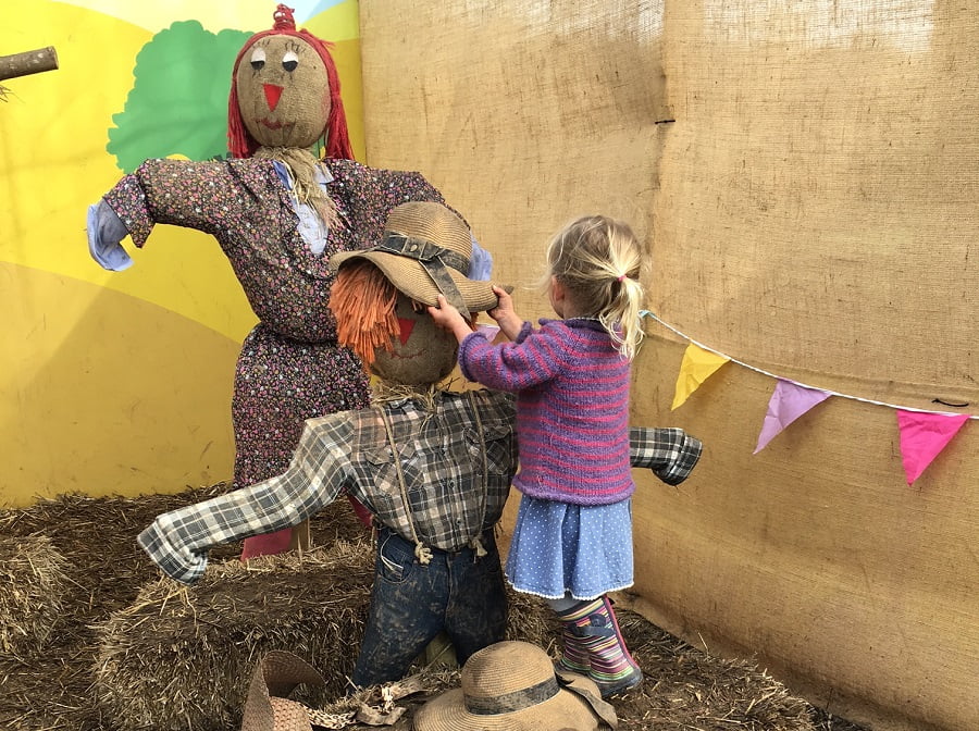 Child dressing two scarecrows at the Lost Gardens of Heligan