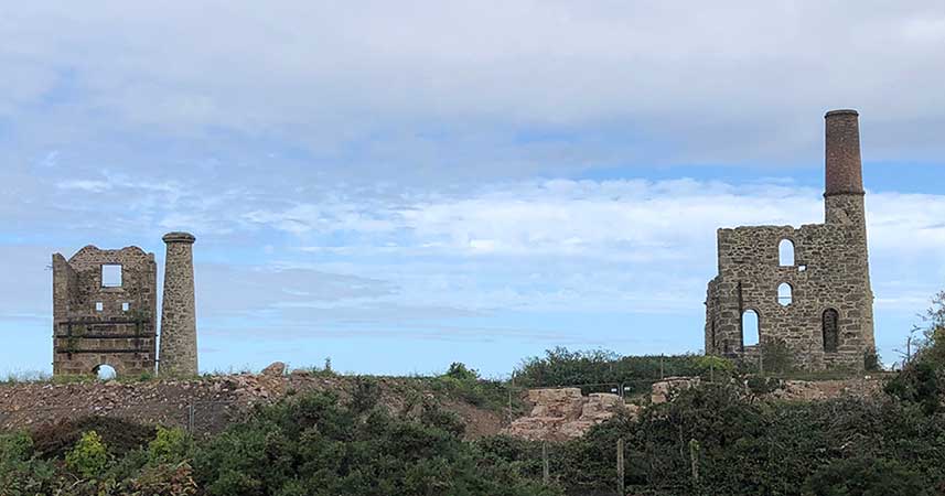 landscape shot of two old tin mine chimneys and walks of building
