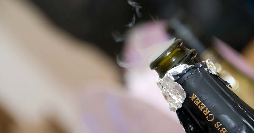 Close up shot of the top of a champagne bottle that's just popped