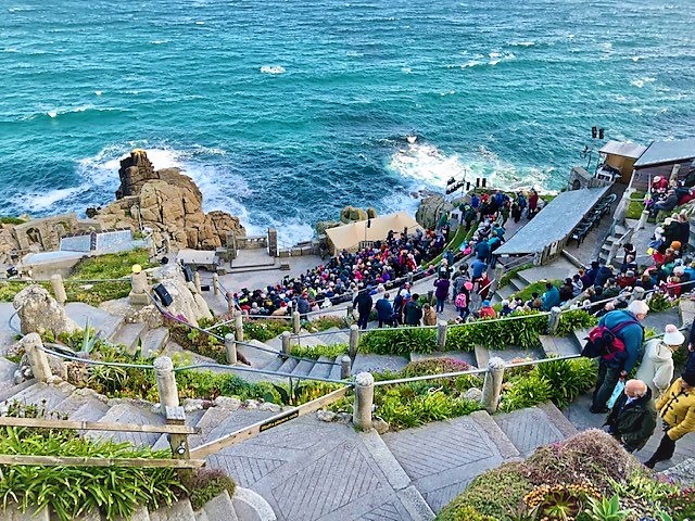Outdoor Theatre on the sea edge with a large crowd walking down the cliff steps