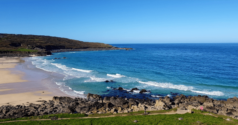 A wide shot of a Cornwall beach on a sunny day.