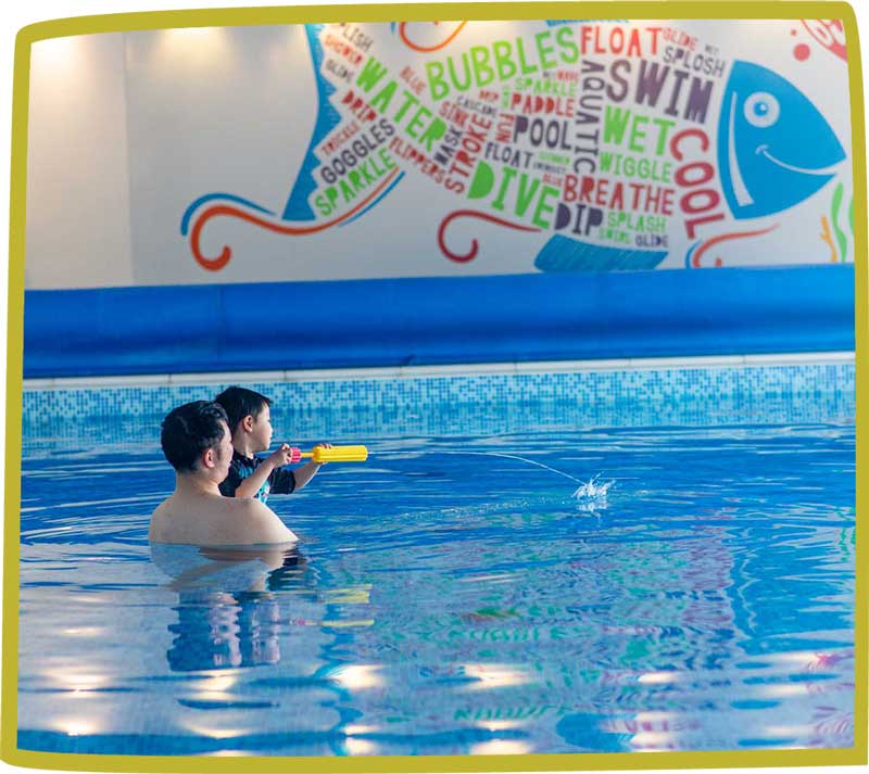 Father and son playing with a water gun with a swimming pool at Bosinver.