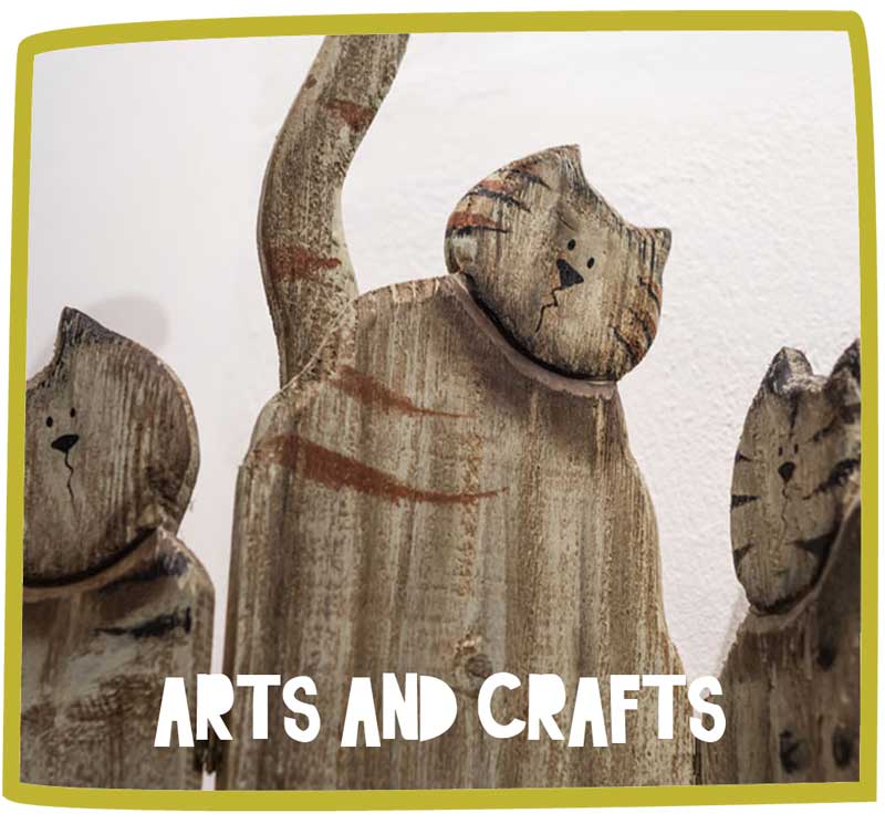 Three wooden cat sculptures positioned against a white wall.