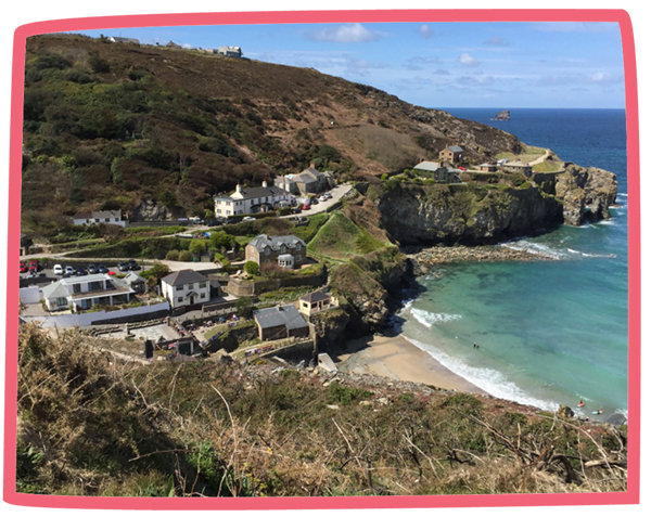 View of a coastal town by a small beach on a sunny day in Cornwall.