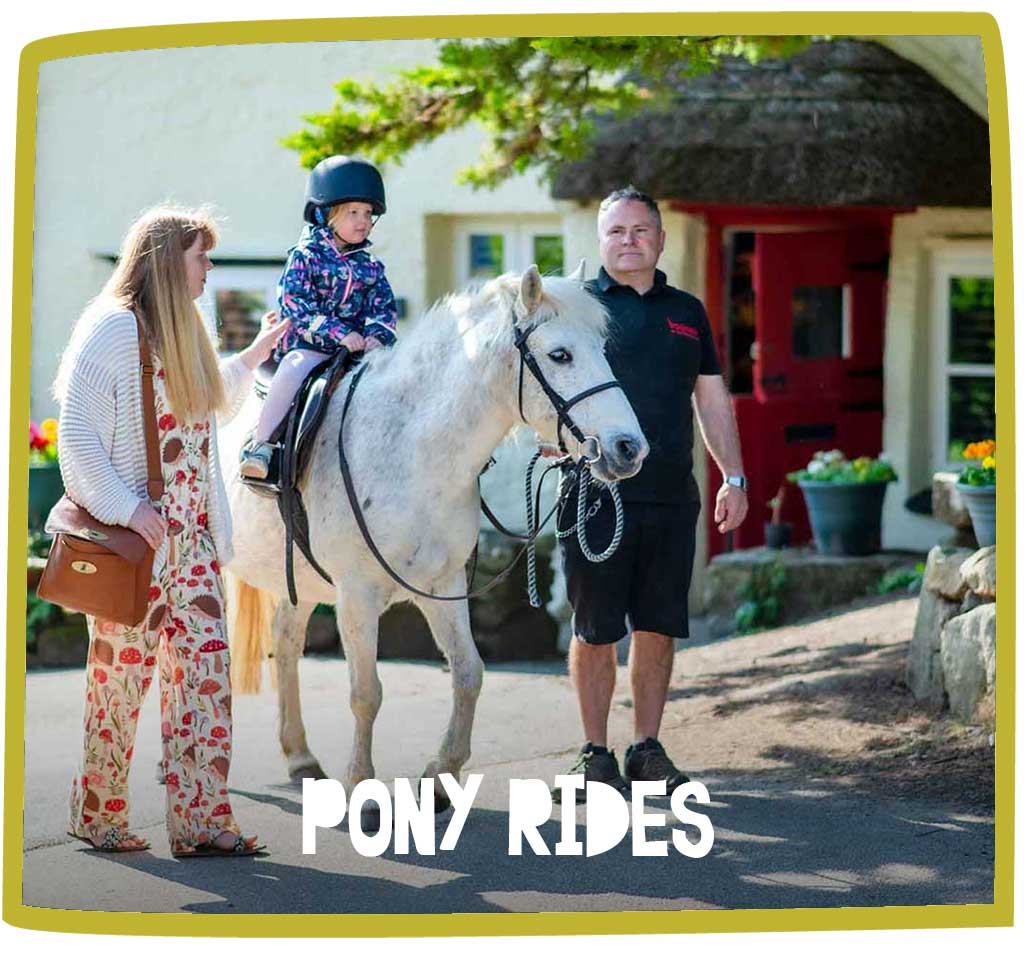 Small child riding a pony at Bosinver whilst adults supervise.