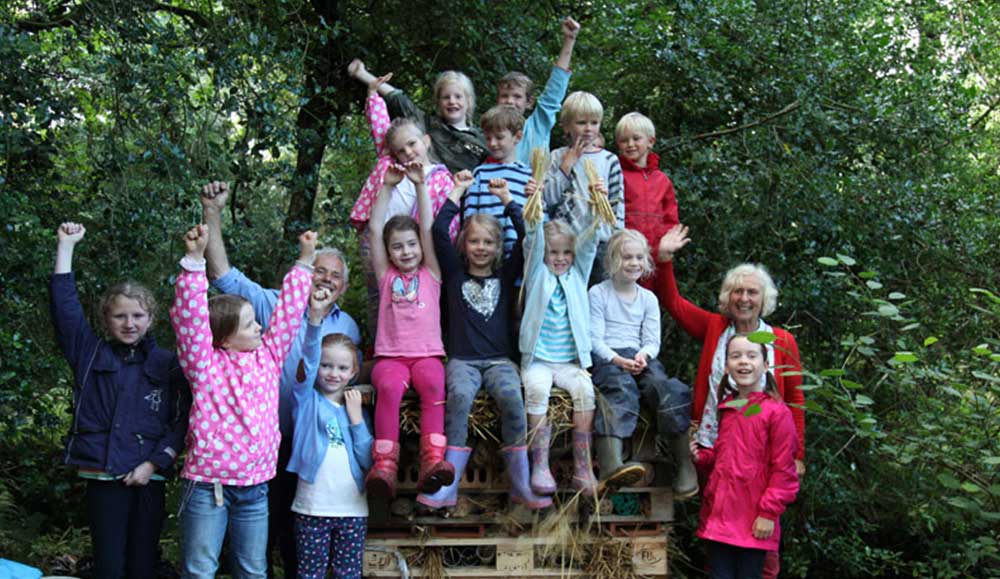 Group of children smiling and waving at Bosinver with two adults.