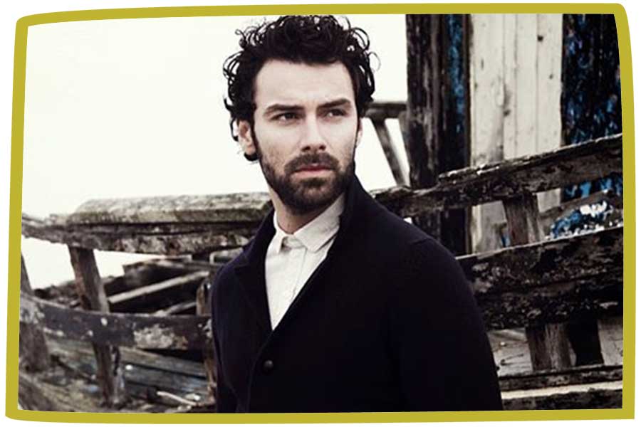 Poldark posing by a wreckage of a boat in Cornwall.
