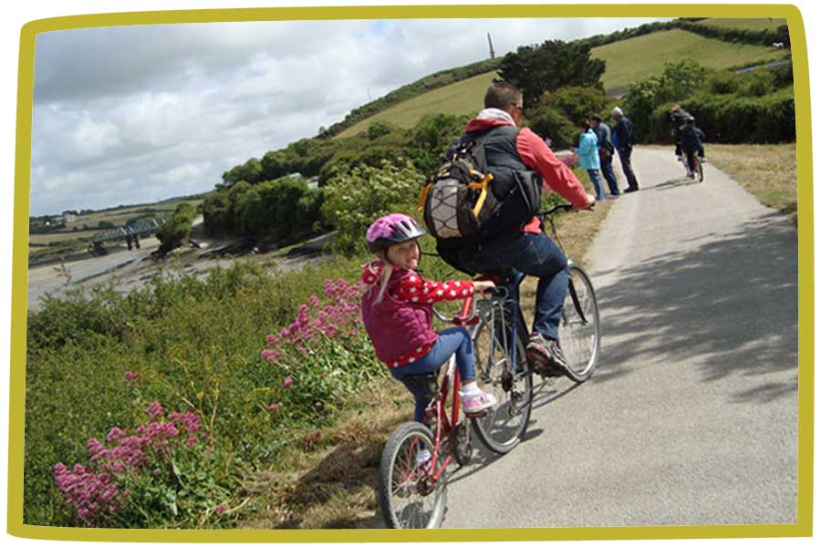 Father and daughter riding on a tandem bike in Cornwall.
