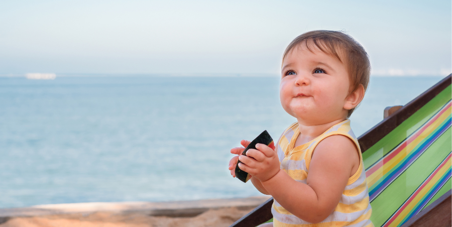 Baby sat on a deckchair at the beach