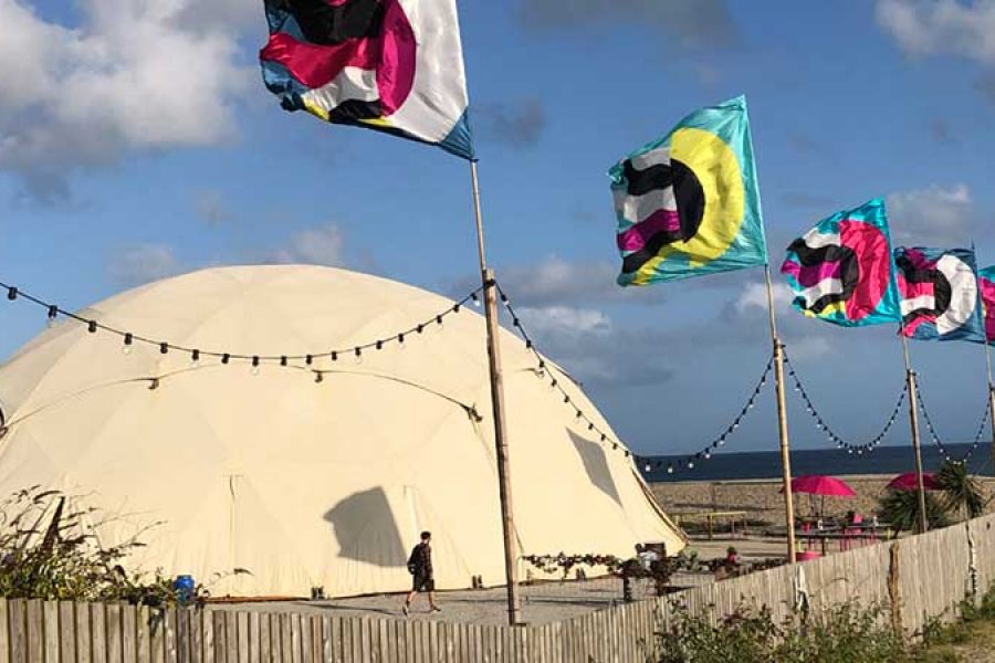 Large dome stage tent on cornish beach with festival flags
